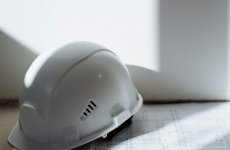 pexels-photo-8470864-8470864 Close-up of a safety helmet and key on a blueprint, symbolizing construction and planning.